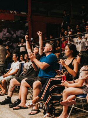 Excited crowd cheering and clapping at an indoor sports event, capturing the energy and enthusiasm.