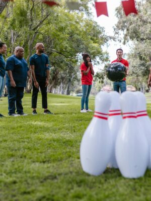 Group of diverse adults enjoying an outdoor bowling activity for team building in a park.