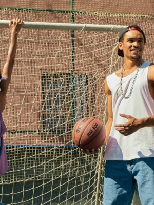 Young adults enjoying basketball game outdoors, showcasing skill and teamwork.