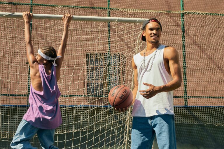 Young adults enjoying basketball game outdoors, showcasing skill and teamwork.